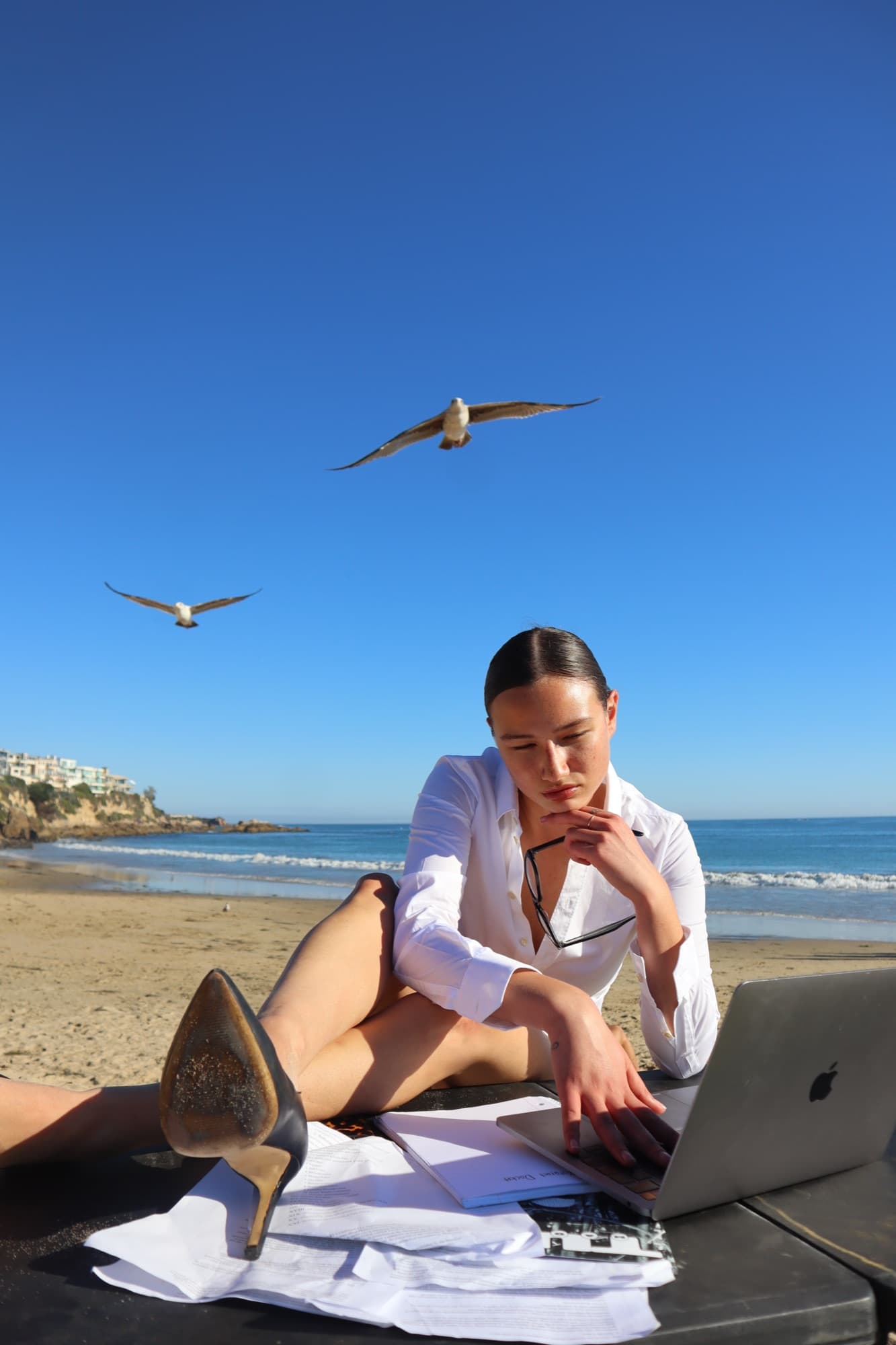 Alyssa Lowry on the beach with a laptop and seagulls overhead