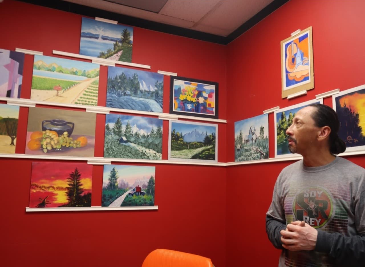 Antonio Palomo with the rescued paintings on the wall of his artist space